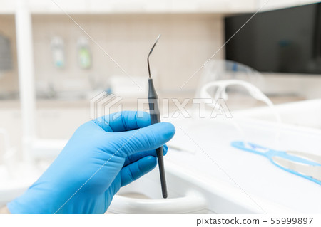 The hand of the dentist in the glove holds tool mirror. Stomatological instrument in the dentist The hand of the dentist in the glove holds tool mirror. Stomatological instrument in the dentist 55999897