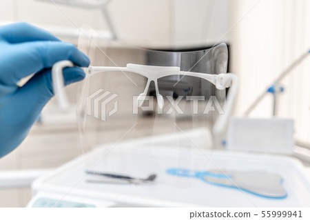 Close-up hand of dentist in the glove holds dental protective mask. Office where dentist conducts 55999941