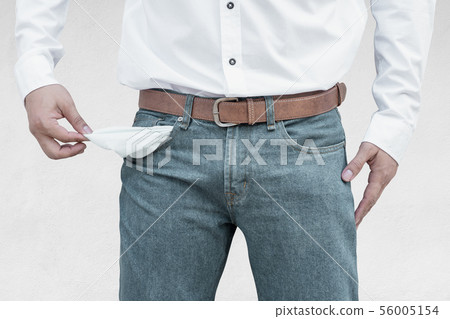 Man showing his empty pockets on wall background. Man showing his empty pockets on wall background. 56005154