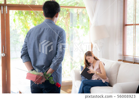 asian couple with man hiding red rose and gift box asian couple with man hiding red rose and gift box 56008923