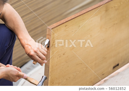 Interior work A joiner crafts processing a sliding door with a chisel in order to attach a door wheel Interior work A joiner crafts processing a sliding door with a chisel in order to attach a door wheel 56012852