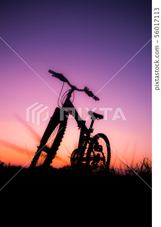 Bicycle on the grass field at sunset Bicycle on the grass field at sunset 56017113