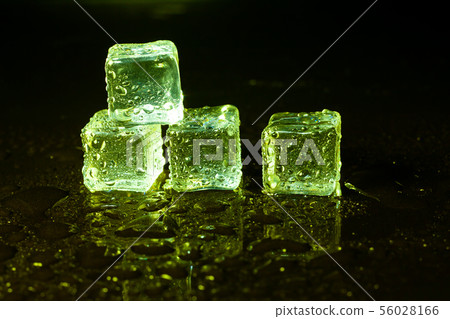 Green ice cubes on black table background. Green ice cubes on black table background. 56028166