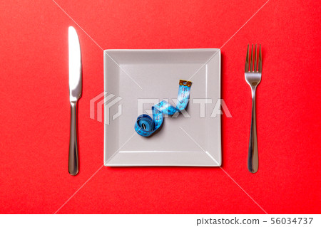 Measuring tape in a plate with fork and knife on 56034737