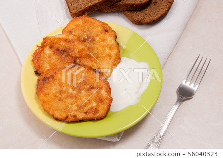 Potato pancakes with meat and sour cream on green Potato pancakes with meat and sour cream on green 56040323