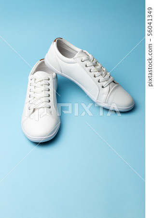 Pair of white sneakers on blue background. Fashion Pair of white sneakers on blue background. Fashion 56041349
