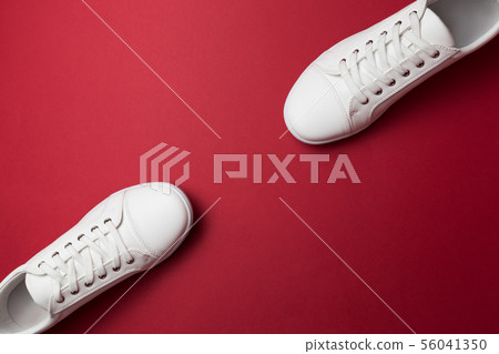 Pair of white trendy sneakers on red background. Pair of white trendy sneakers on red background. 56041350