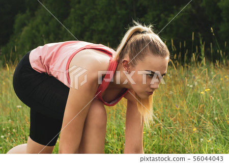 young woman in low start position before jogging young woman in low start position before jogging 56044043
