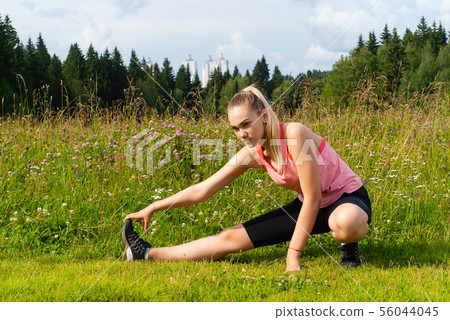 young woman doing exercises stretching in a meadow young woman doing exercises stretching in a meadow 56044045