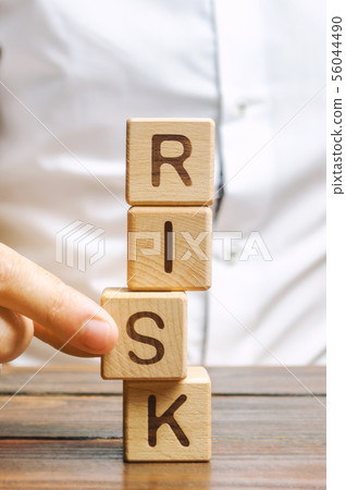 Man removes blocks with the word Risk. Man removes blocks with the word Risk. 56044490