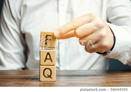 Businessman puts wooden blocks with the word FAQ 56044505