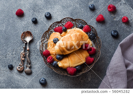 Croissants with fresh raspberries and blueberries  56045282