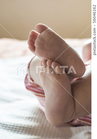 Baby feet close-up on bed. 56046162