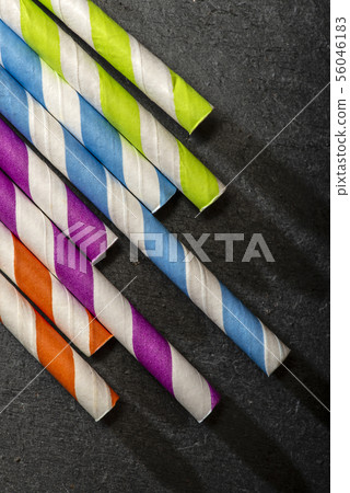Multicoloured drink straws on dark stone 56046183