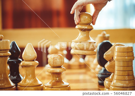 hand holding a chess piece over the Board 56046827
