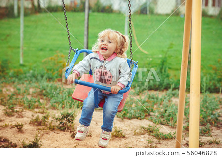 a child swinging on a swing 56046828