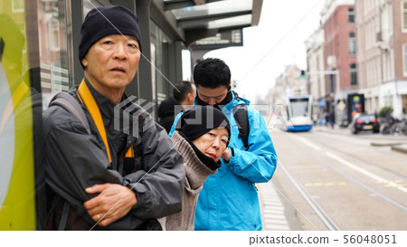 Asian family waiting for bus at bus stop in Europe 56048051