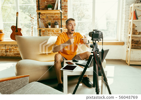 Caucasian male blogger with camera recording video review of gadgets at home 56048769