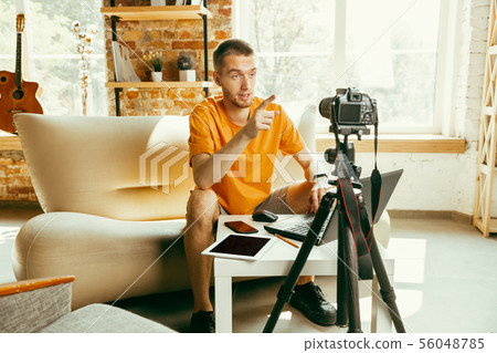 Caucasian male blogger with camera recording video review of gadgets at home 56048785