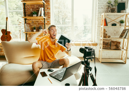 Caucasian male blogger with camera recording video review of gadgets at home 56048786