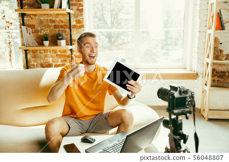Caucasian male blogger with camera recording video review of gadgets at home 56048807