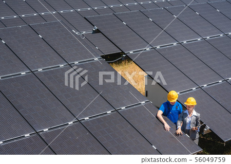 Two people standing amid solar cells in a power plant 56049759