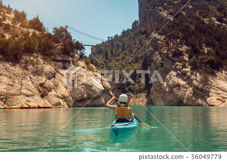 Woman in kayak on a river crossing a gorge in the Pyrenees mountains Woman in kayak on a river crossing a gorge in the Pyrenees mountains 56049779
