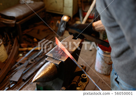 Blacksmith forging red-hot metal with hammer. 56050001