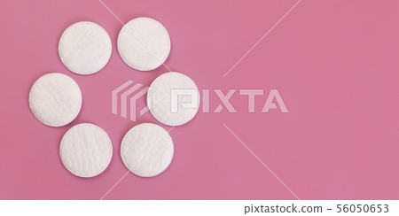 Top down view, 6 face cleaning cotton pads arranged in circle, on pink board, wide banner space for 56050653