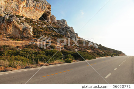 Evening sun shines on sharp rocks by the asphalt road - typical scenery on Karpasia peninsula in 56050771
