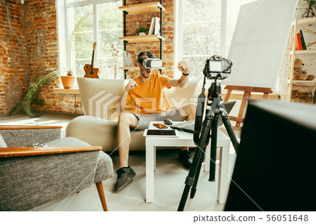 Caucasian male blogger with camera recording video review of gadgets at home Caucasian male blogger with camera recording video review of gadgets at home 56051648