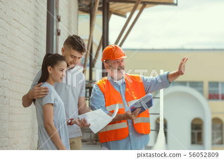 Foreman or achitect shows house, office or store design plans to a young couple 56052809