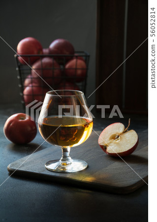 Glass with Calvados brandy and red apples on black. Glass with Calvados brandy and red apples on black. 56052814