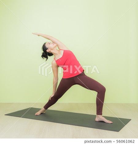 Asian woman doing warrior pose yoga. 56061062