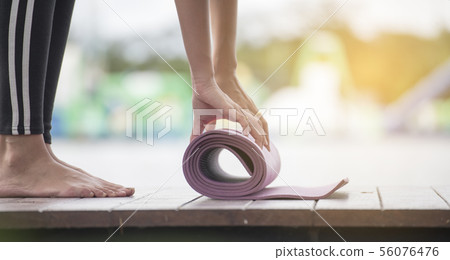 Beautiful Healthy woman rolling yoga mattress Beautiful Healthy woman rolling yoga mattress 56076476