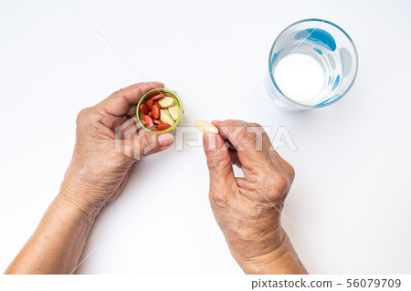 Senior woman's hands pick pills in bottle, glass Senior woman's hands pick pills in bottle, glass 56079709