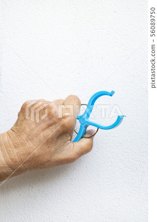 Senior woman's hand squeezing plastic clothes peg 56089750