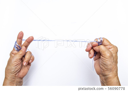 Senior woman's hands pull plastic rope on white Senior woman's hands pull plastic rope on white 56090778