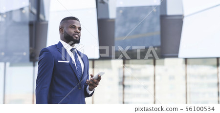 Pensive Black Business Man Holding Smartphone Standing In Urban Area Pensive Black Business Man Holding Smartphone Standing In Urban Area 56100534