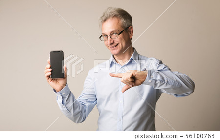 Senior man presenting smartphone and pointing on it 56100763