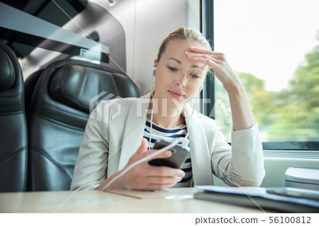 Businesswoman communicating on mobile phone while traveling by train. Businesswoman communicating on mobile phone while traveling by train. 56100812