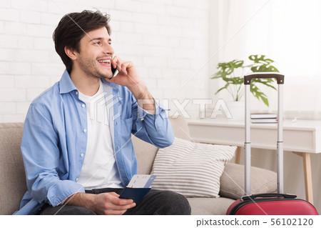 Young man talking on phone, holding passport and ticket Young man talking on phone, holding passport and ticket 56102120
