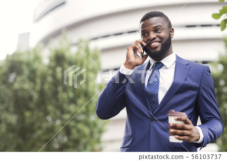African American employee talking on mobile phone having coffee break 56103737