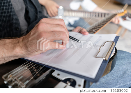 Older brother explains to his younger one how to use notes on music sheets on an exapmple 56105002