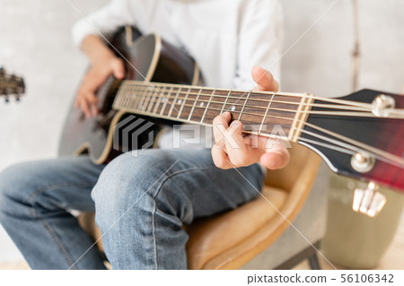 European male posing with acoustic guitar in his hands 56106342