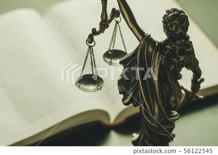 Figure of Justice standing over a law book 56122545