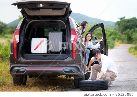 Father change tire and his family waiting between 56123095