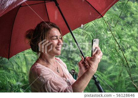 Woman with a red umbrella takes picture by Woman with a red umbrella takes picture by 56128646