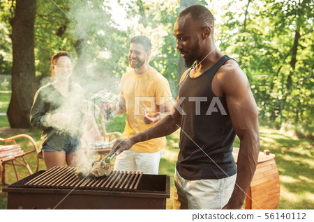 Happy friends are having beer and barbecue party at sunny day 56140112