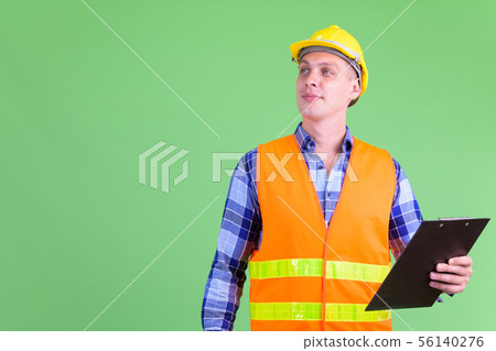 Young man construction worker thinking while holding clipboard 56140276